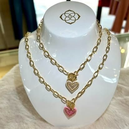 A necklace with three hearts on it is on a mannequin.