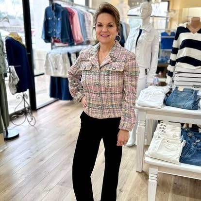 A woman is standing in a clothing store with her hands on her hips.