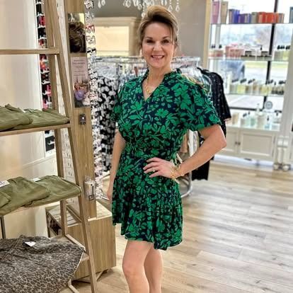 A woman in a green dress is standing in a store.