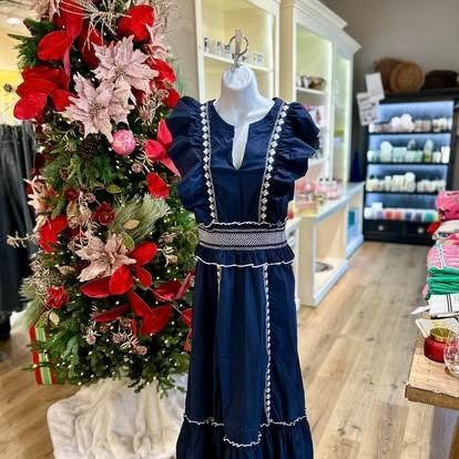 A blue dress is on a mannequin in front of a christmas tree