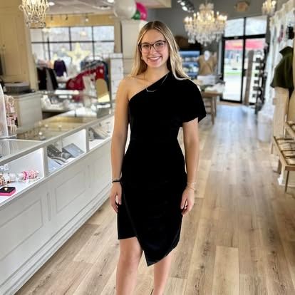 A woman in a black dress is standing in a store.