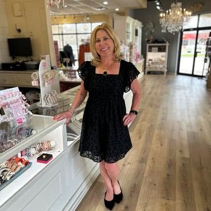 A woman in a black dress is standing in a store.