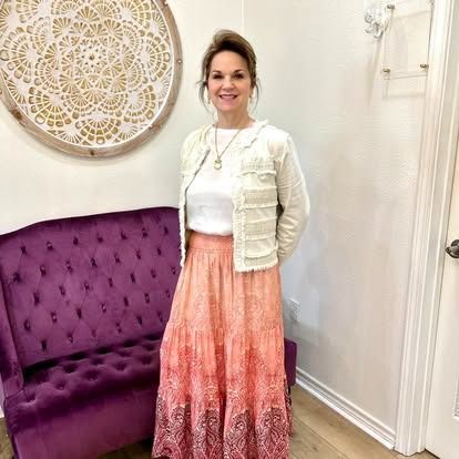 A woman in a long skirt is standing in front of a purple couch.