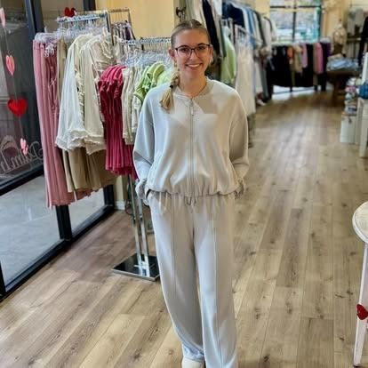 A woman in a white outfit is standing in a clothing store.