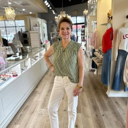 A woman is standing in a clothing store with her hands on her hips.