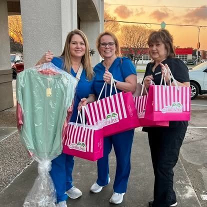 Three women are standing next to each other holding shopping bags.