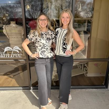 Two women are posing for a picture in front of a store.