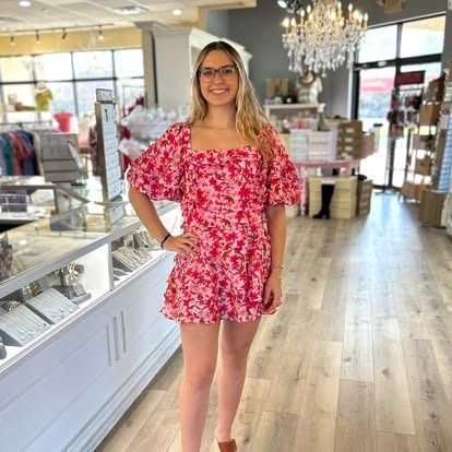 A woman in a pink floral dress is standing in a store.