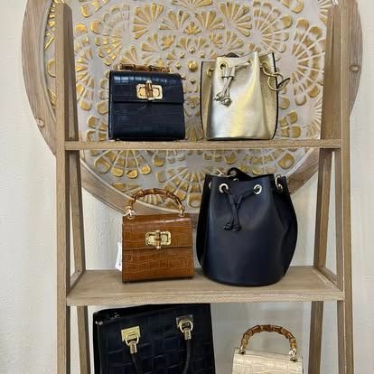 A wooden shelf with a variety of handbags on it.