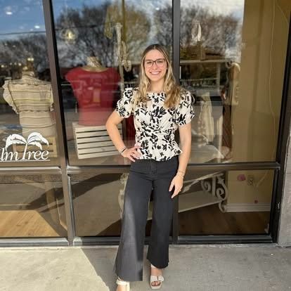 A woman is standing in front of a store window.