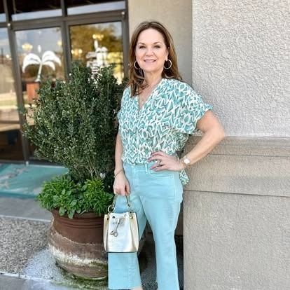 A woman is standing in front of a building holding a purse.