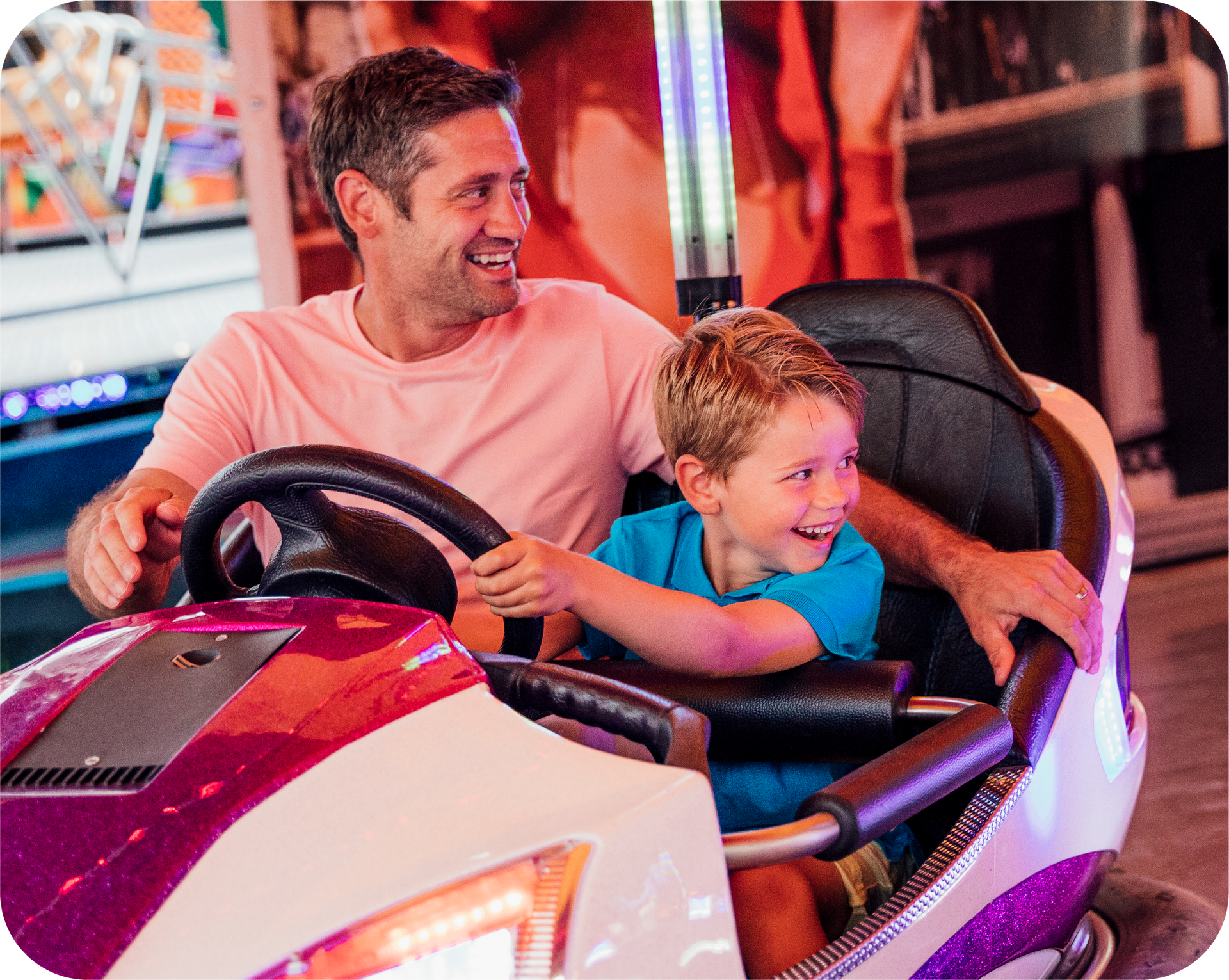 A man and a boy are riding a bumper car at an amusement park.