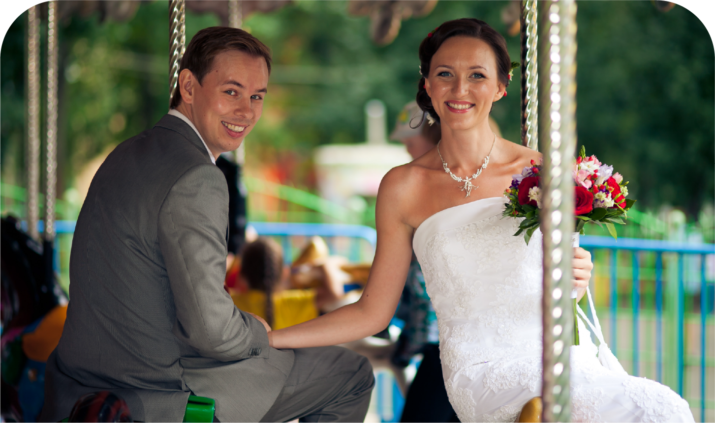 A bride and groom are posing for a picture on a merry go round