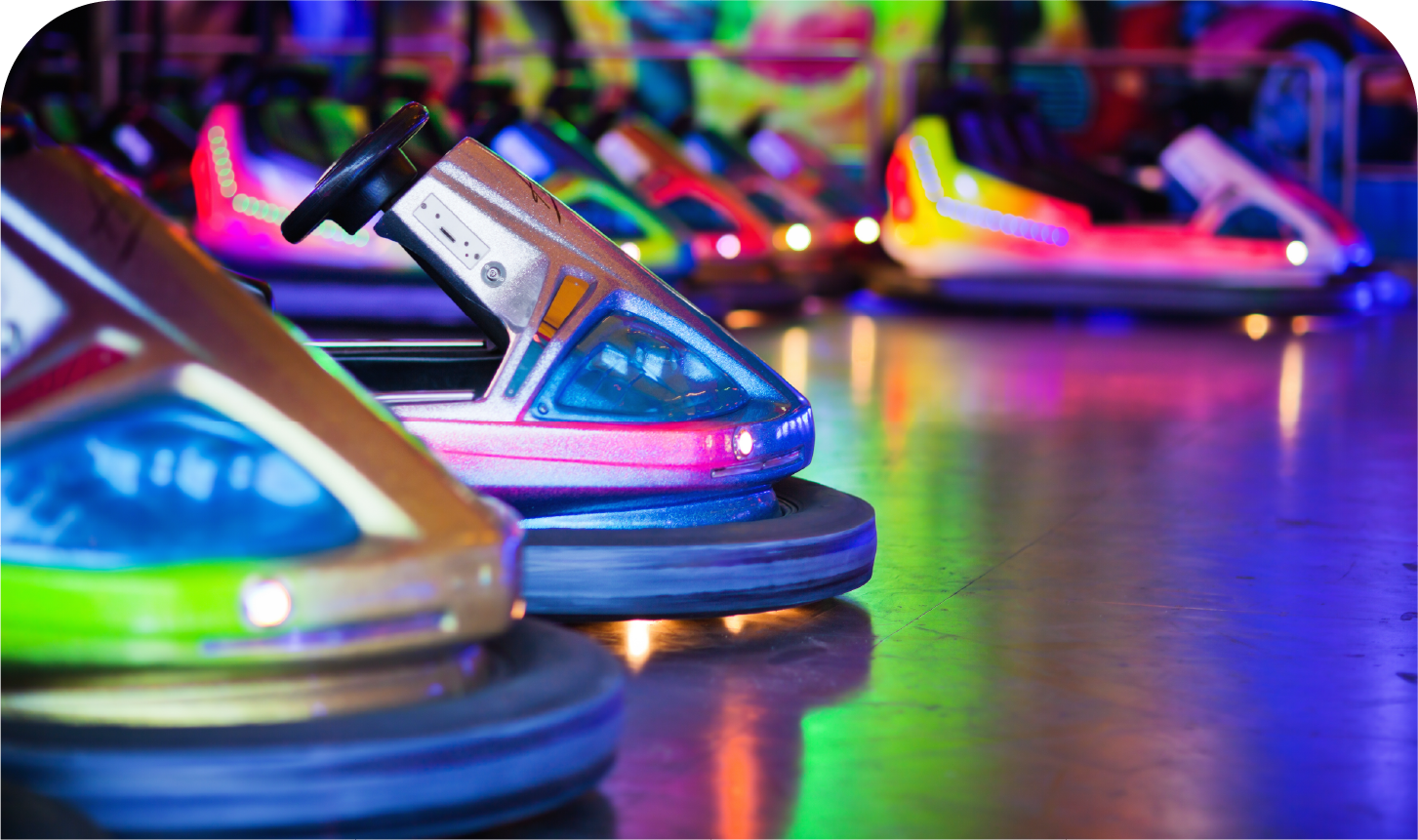 A row of colorful bumper cars are lined up in an amusement park.