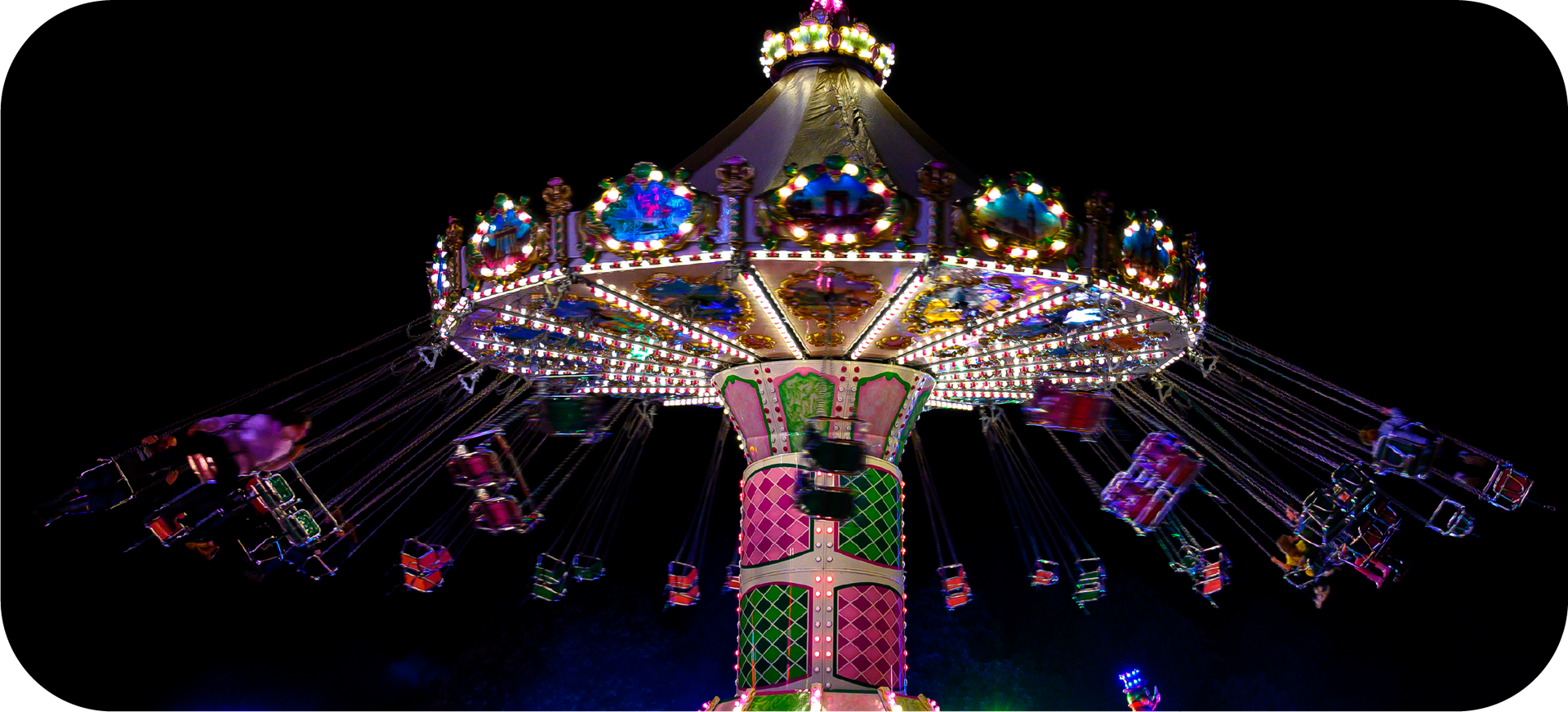 A carnival ride is lit up at night with people riding it.