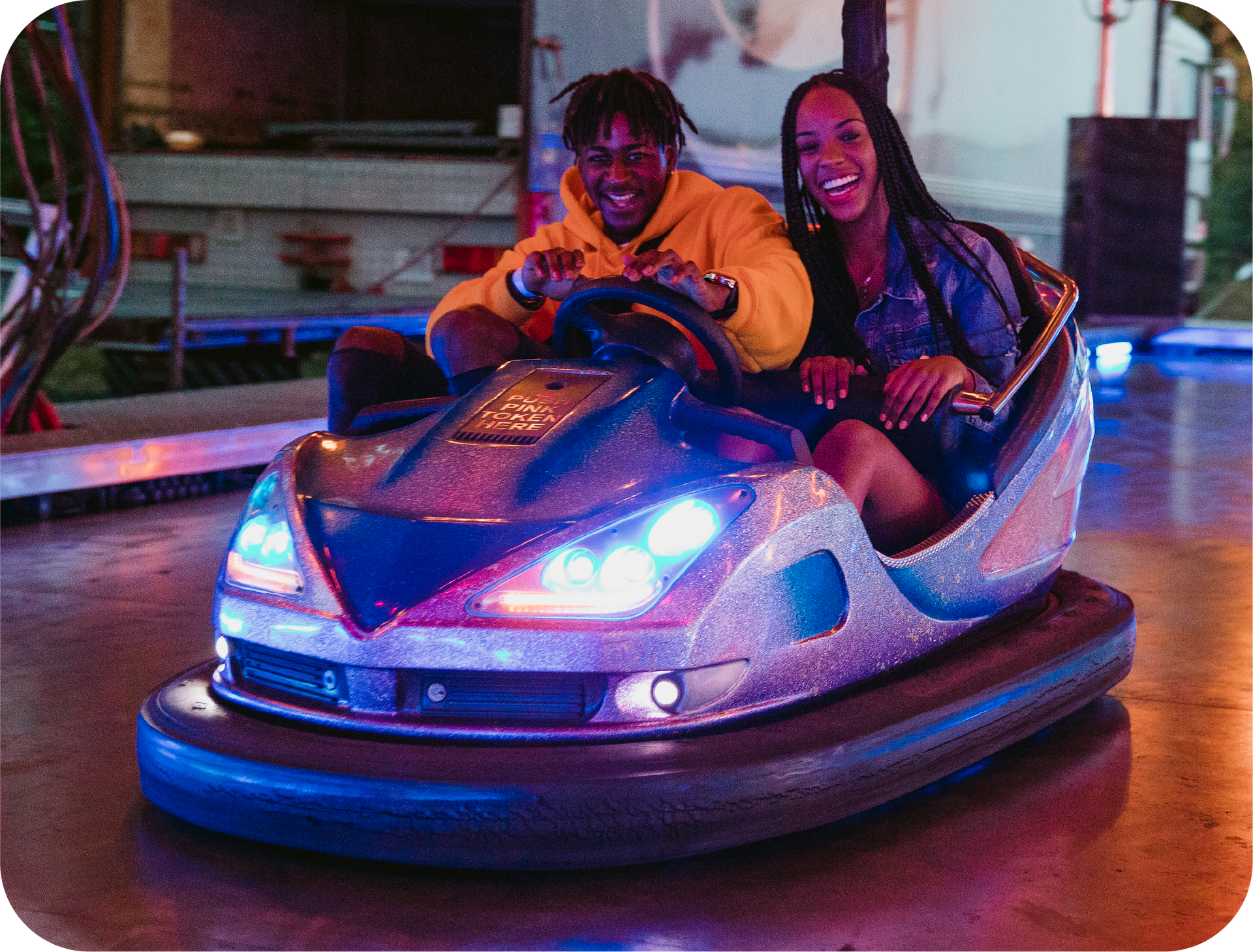 A man and a woman are riding a bumper car at an amusement park.