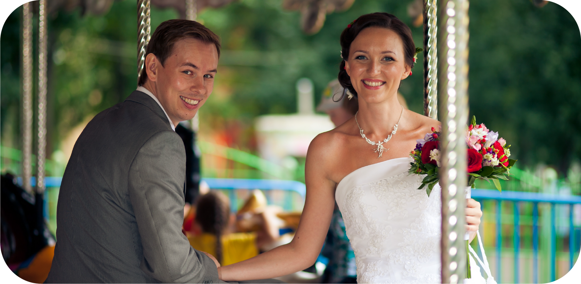 A bride and groom are posing for a picture on a merry go round.