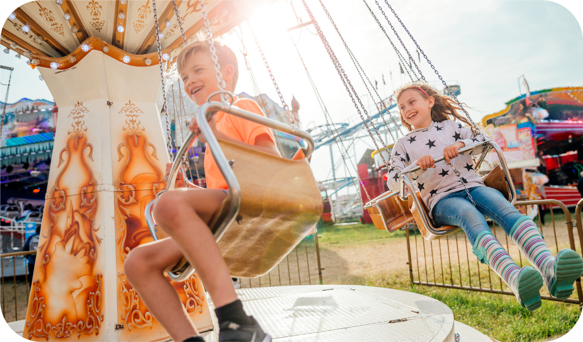 A boy and a girl are riding a merry go round at a carnival.