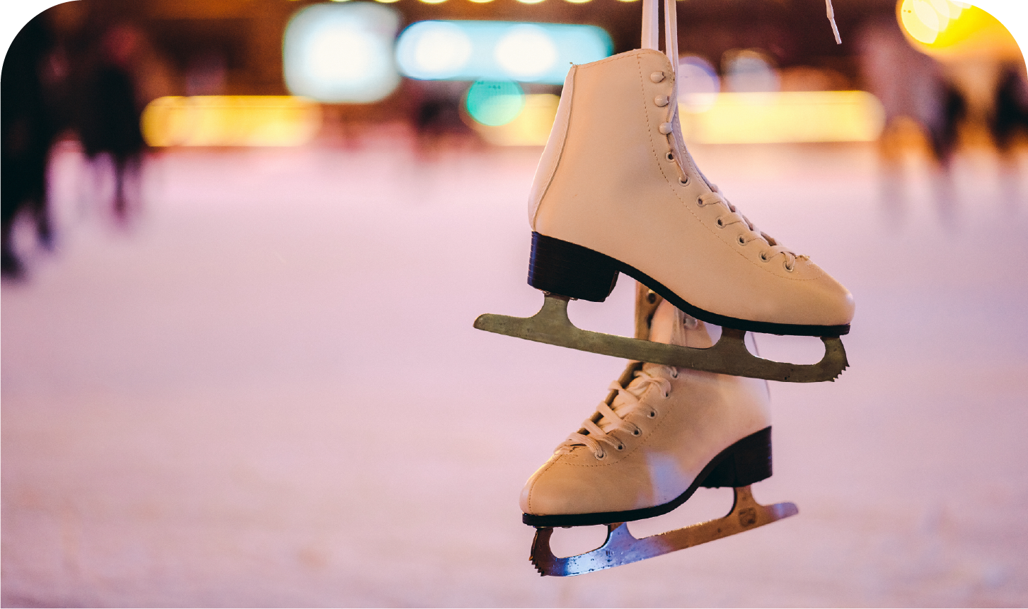 A pair of ice skates hanging from a rope on a ice rink.