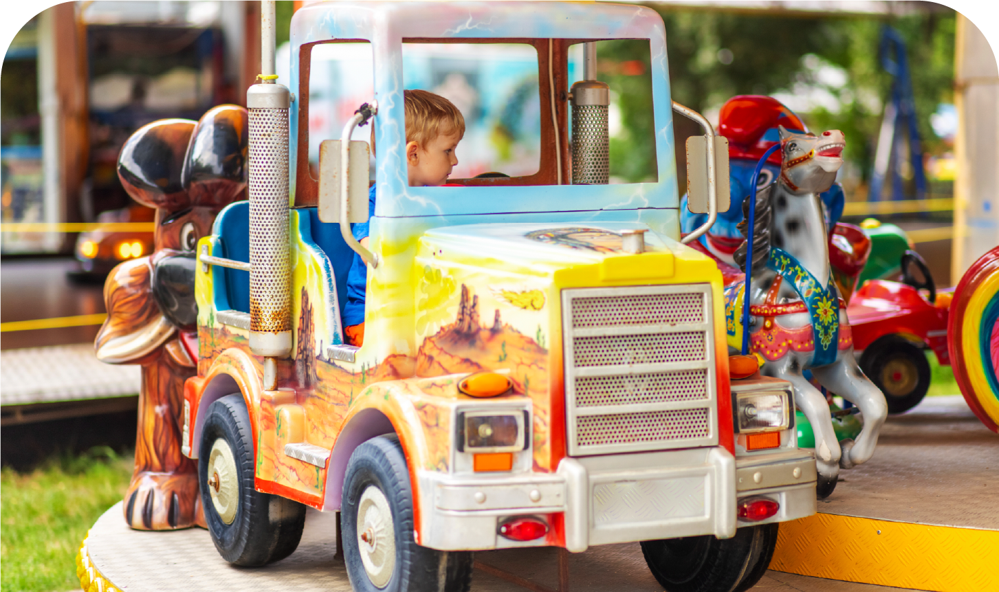 A child is riding a toy truck on a merry go round.