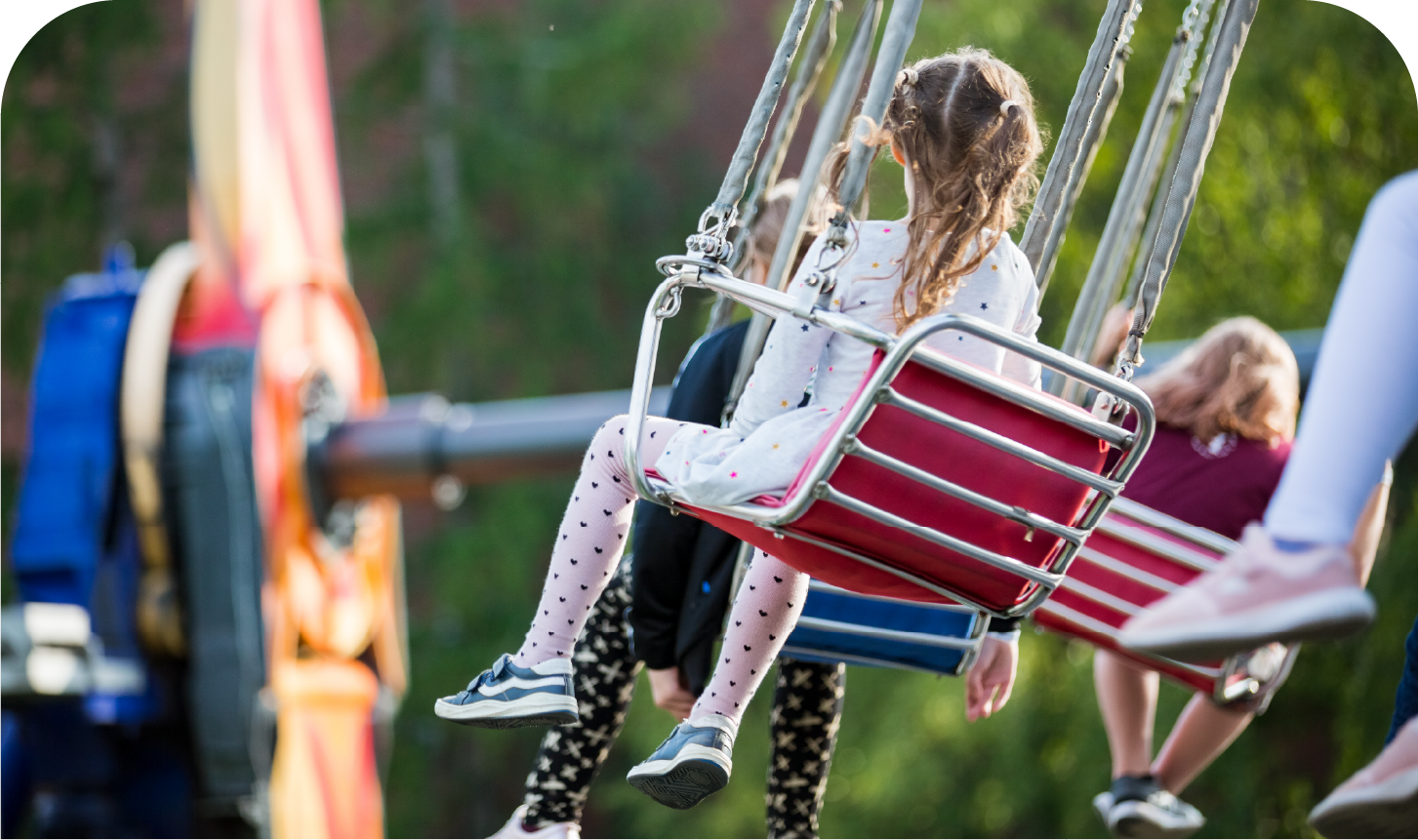 A group of children are riding a swing ride at an amusement park.