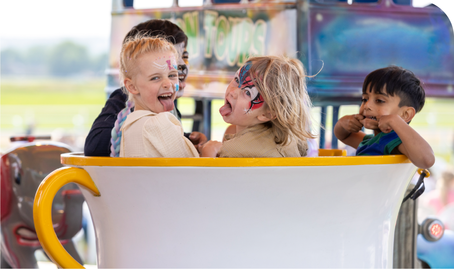 A group of children are riding in a tea cup at a carnival.