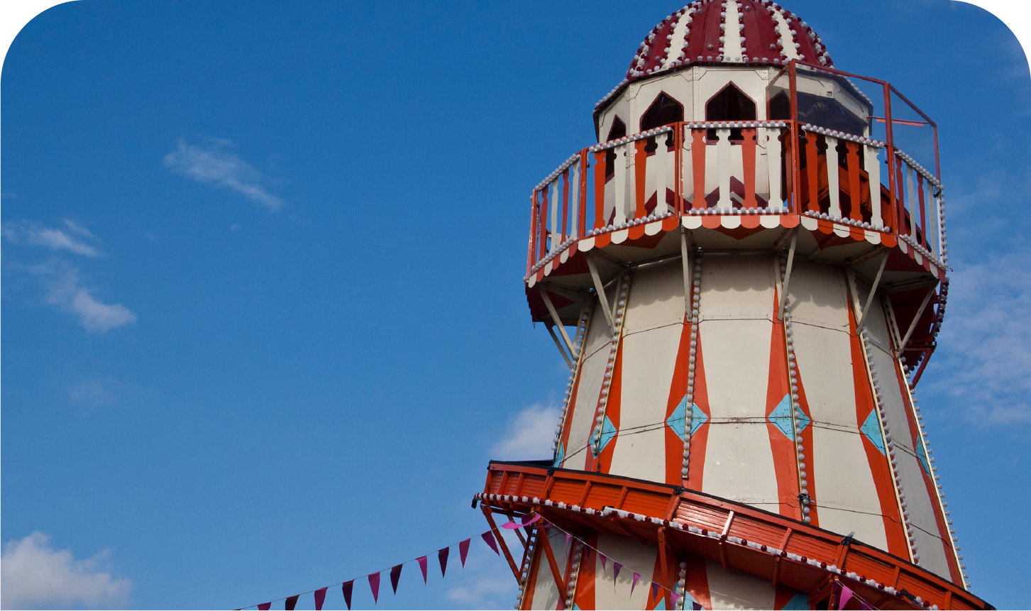 A red and white ferris wheel with a blue sky in the background