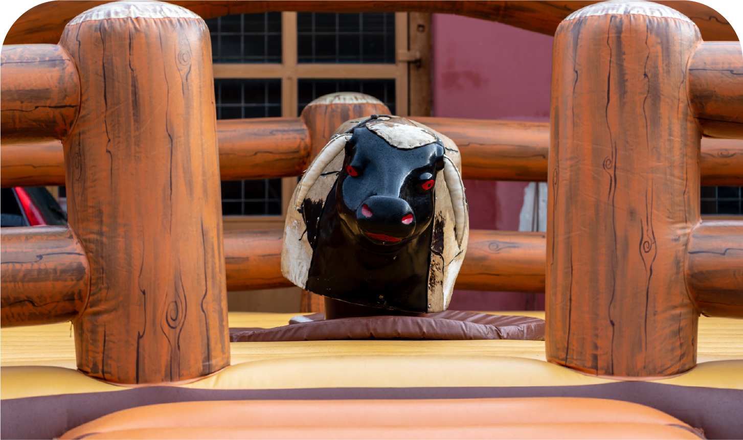 A bull is behind a wooden fence in a rodeo.