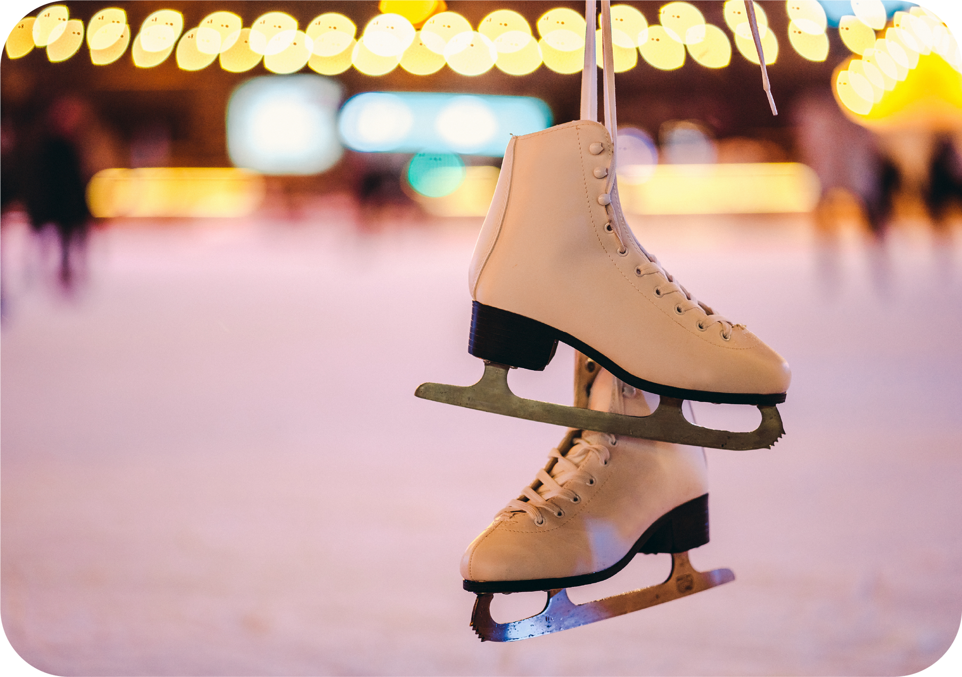 A pair of ice skates hanging from a string on an ice rink.