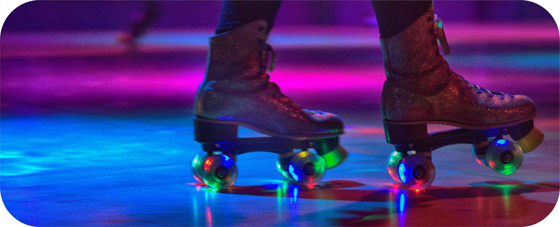 A person is rollerblading on a rink with lights on the wheels.