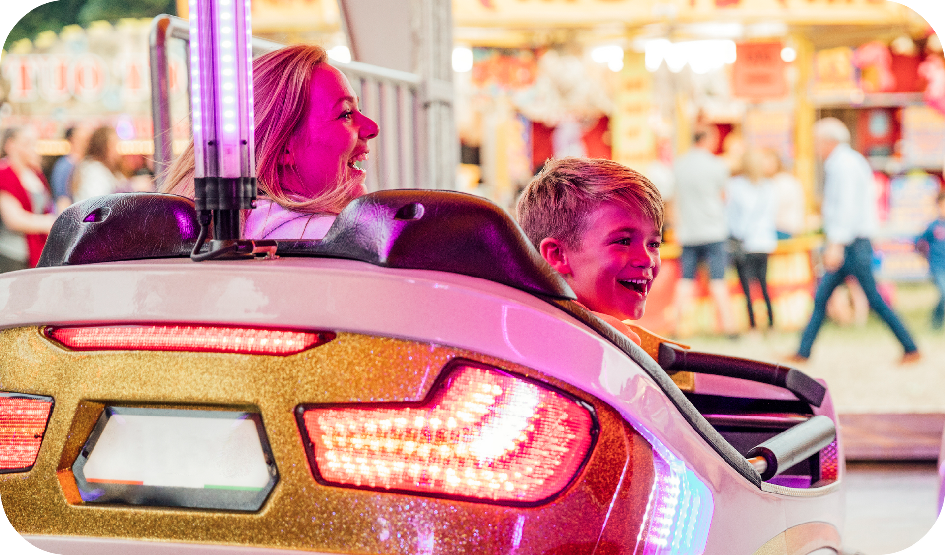 A woman and a boy are riding a roller coaster at a carnival.