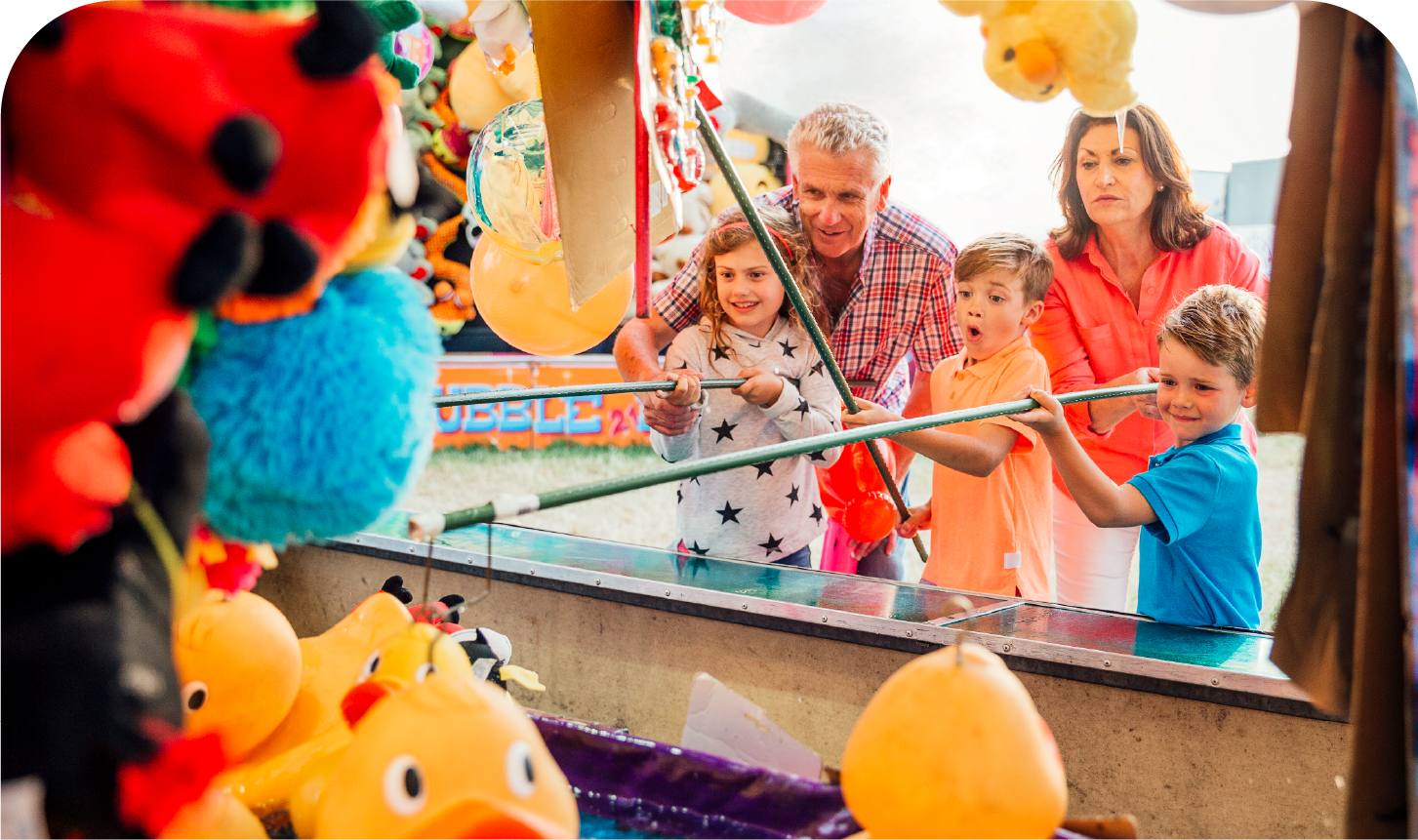 A family is playing a game with rubber ducks at a carnival.