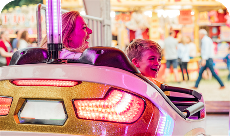 A woman and a boy are riding a roller coaster at a carnival.