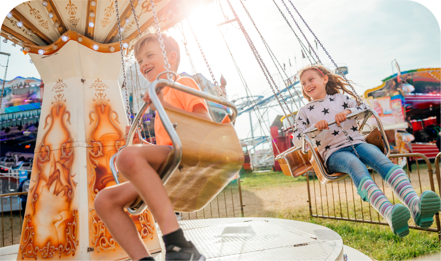 A boy and a girl are riding a merry go round at an amusement park.