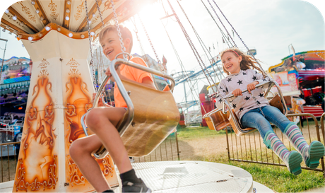 A boy and a girl are riding a merry go round at an amusement park.