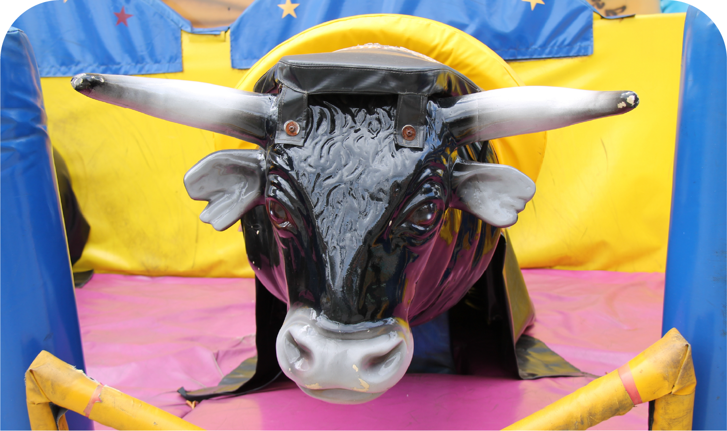 A mechanical bull is sitting in a fenced in area.