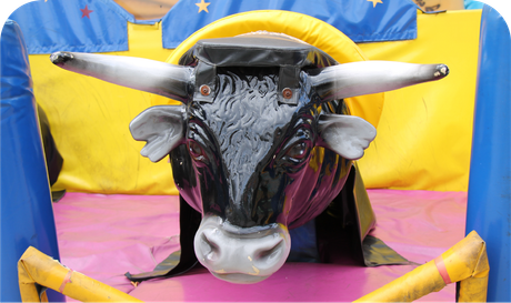 A mechanical bull is sitting in a fenced in area.