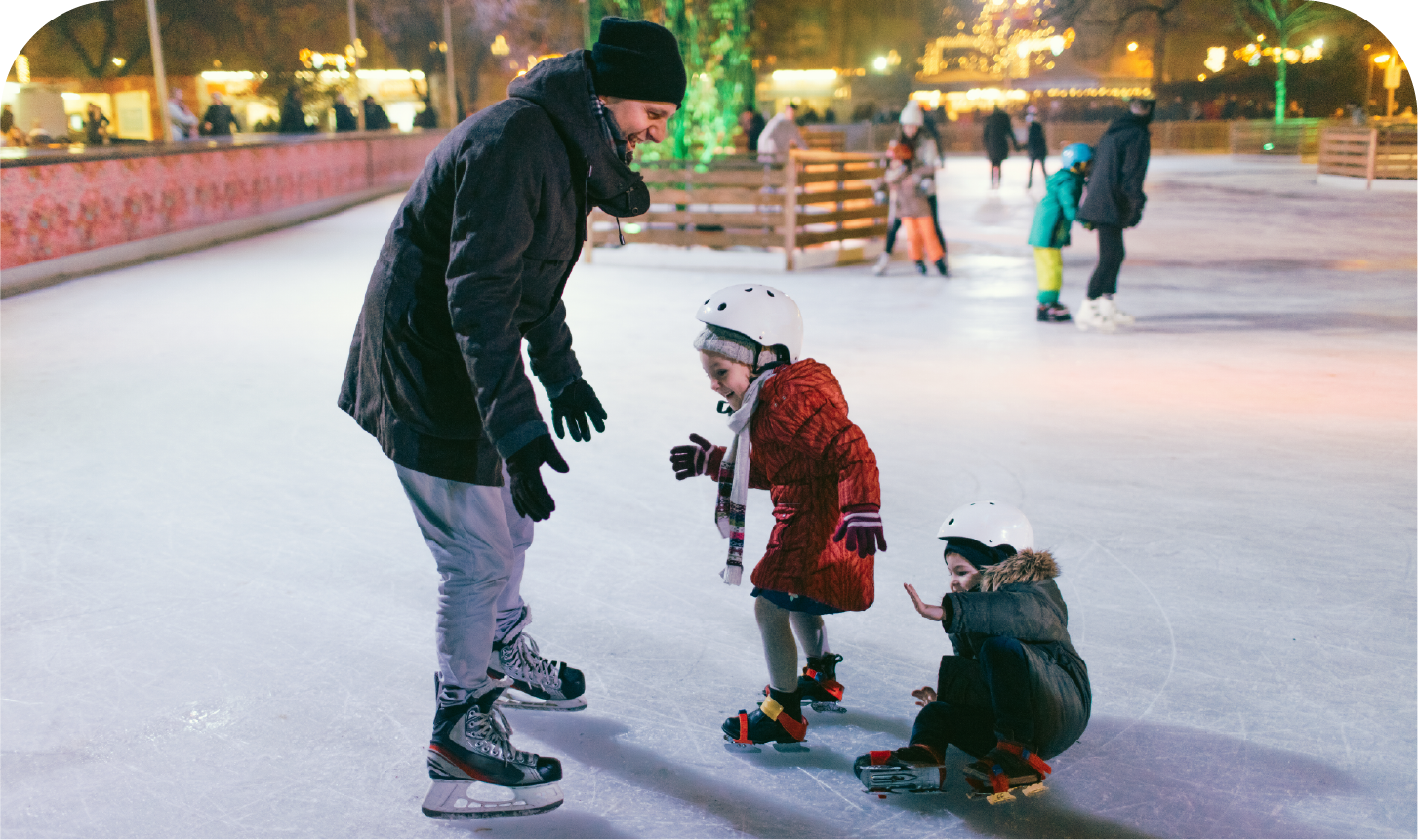 A man is helping two children ice skate on an ice rink.