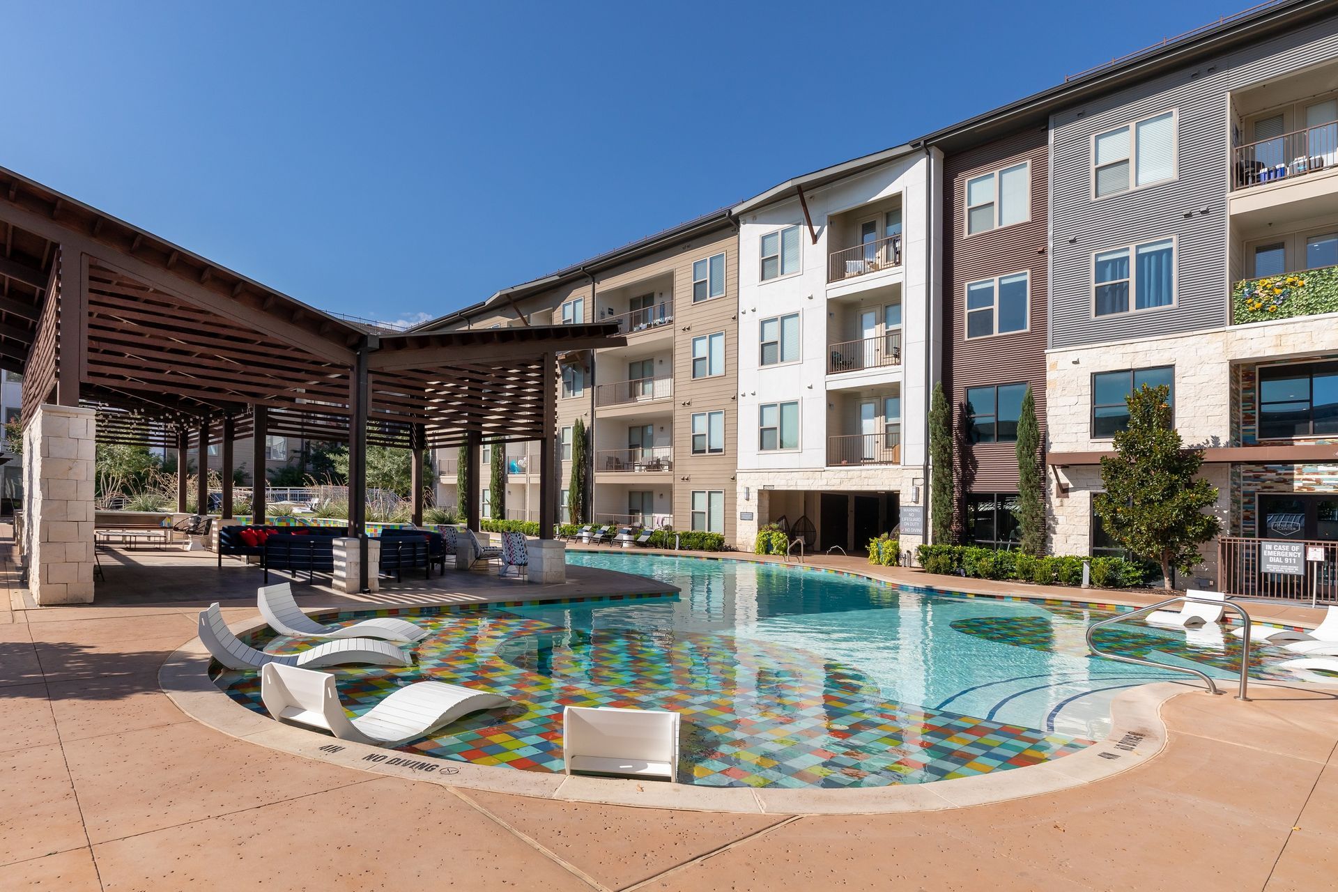 A large swimming pool in front of a large apartment building.