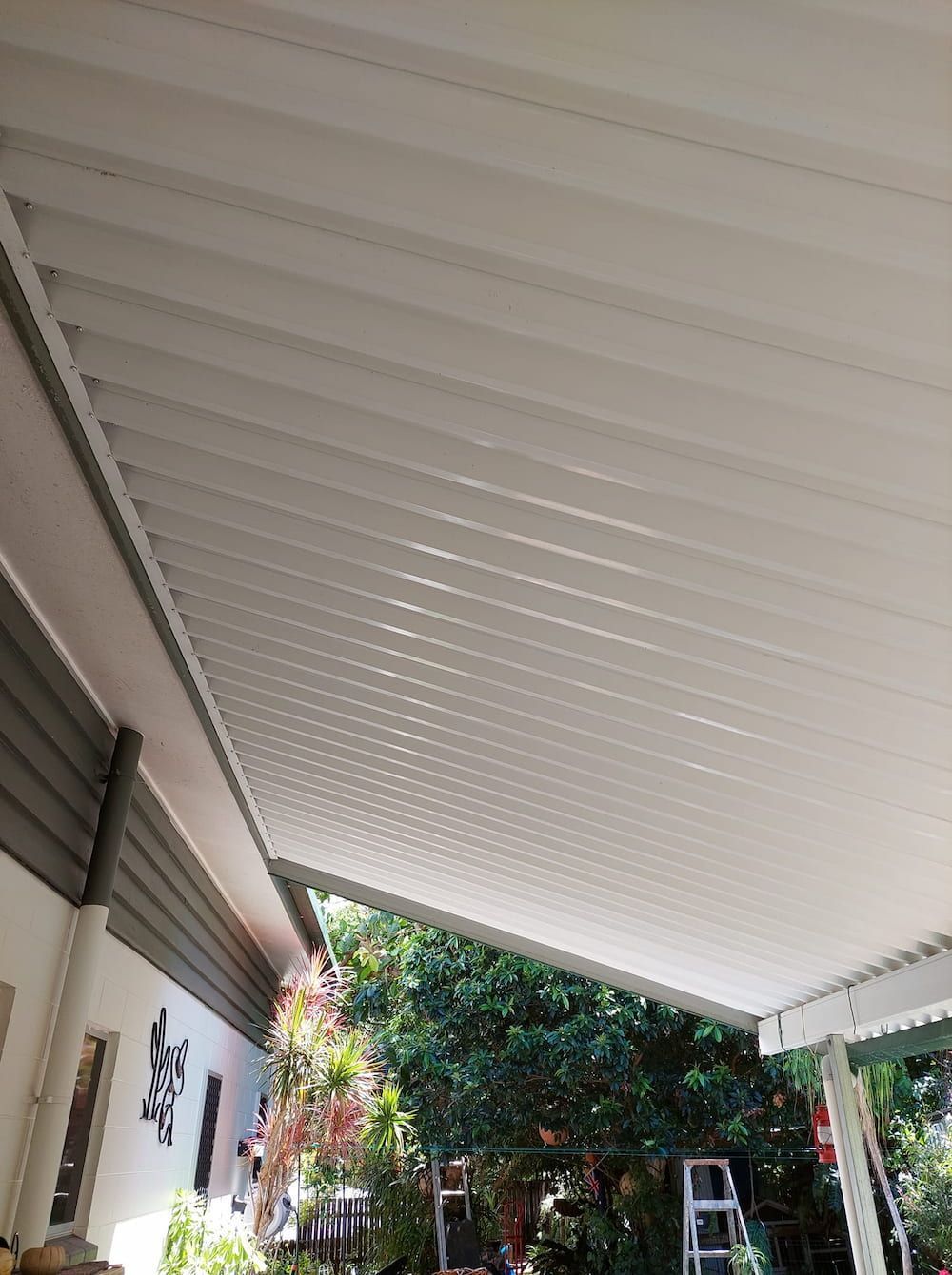 White Patio Cover Attached to a Home, Extending Over a Yard With Trees — DAH Cleaning Services In Bungalow, QLD