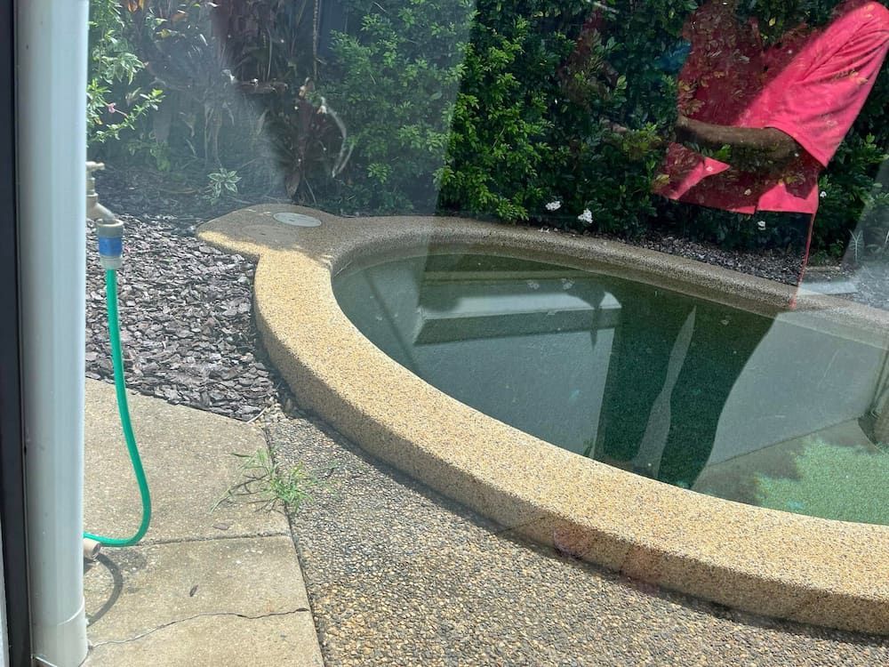 A Small, Oval-shaped Pool With a Tan Border, Viewed Through a Window — DAH Cleaning Services In Bungalow, QLD