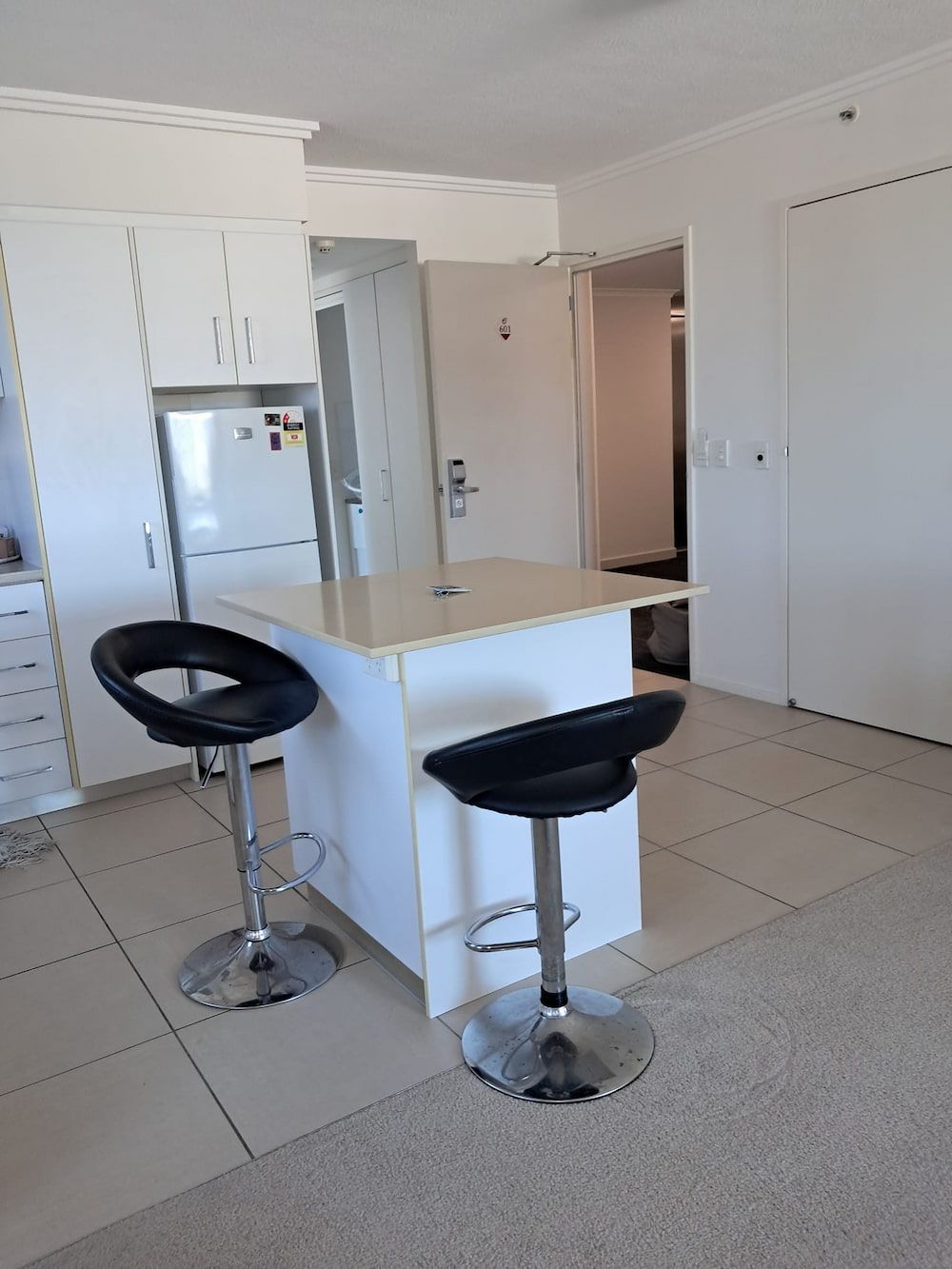 Kitchen With a White Island, Two Black Bar Stools, and White Cabinets — DAH Cleaning Services In Bungalow, QLD