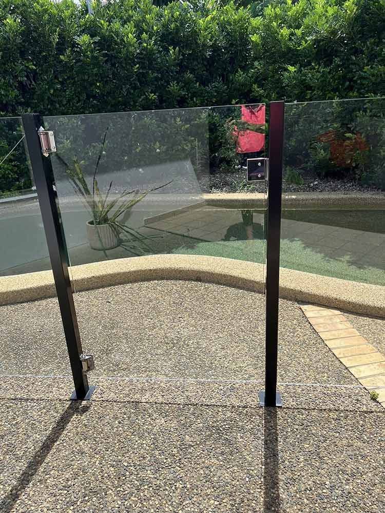 Glass Pool Gate With Black Frame, Set on a Concrete Patio — DAH Cleaning Services in Bungalow, QLD