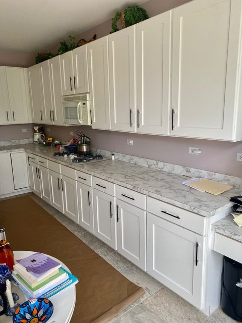 White kitchen cabinets and countertops; microwave and stove visible.