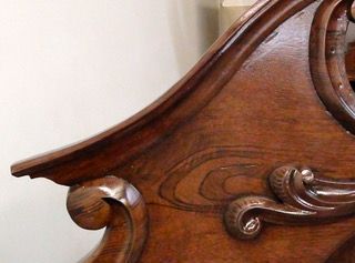Close-up of ornate, dark wooden furniture detail with curved edges and carved flourishes.