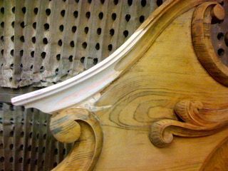 Close-up of ornate wooden furniture with white trim and carved details, showing wood grain.