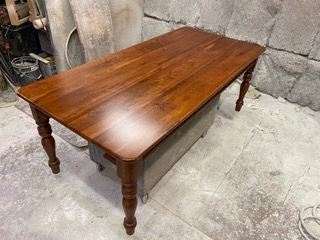 Wooden dining table with rounded corners and turned legs, indoors.