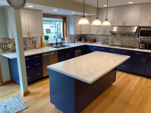 White kitchen cabinets with appliances and black countertop on hardwood floor.