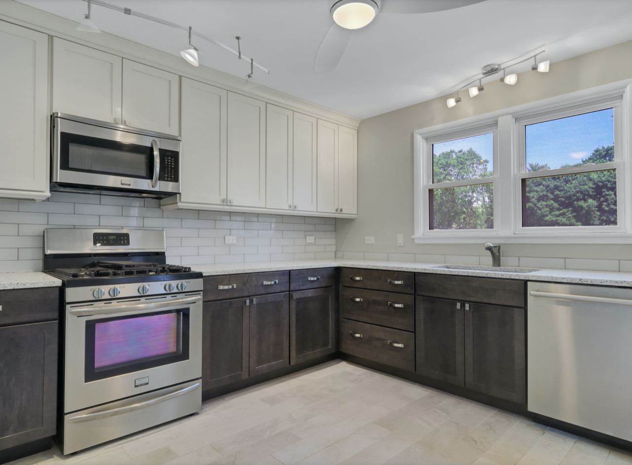 Modern kitchen with stainless steel appliances, dark and light cabinets, and white subway tile backsplash.