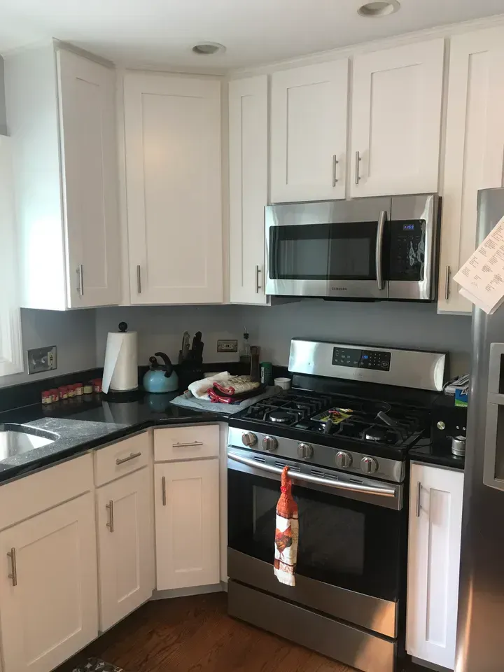 White kitchen cabinets with stainless steel appliances, black countertop.